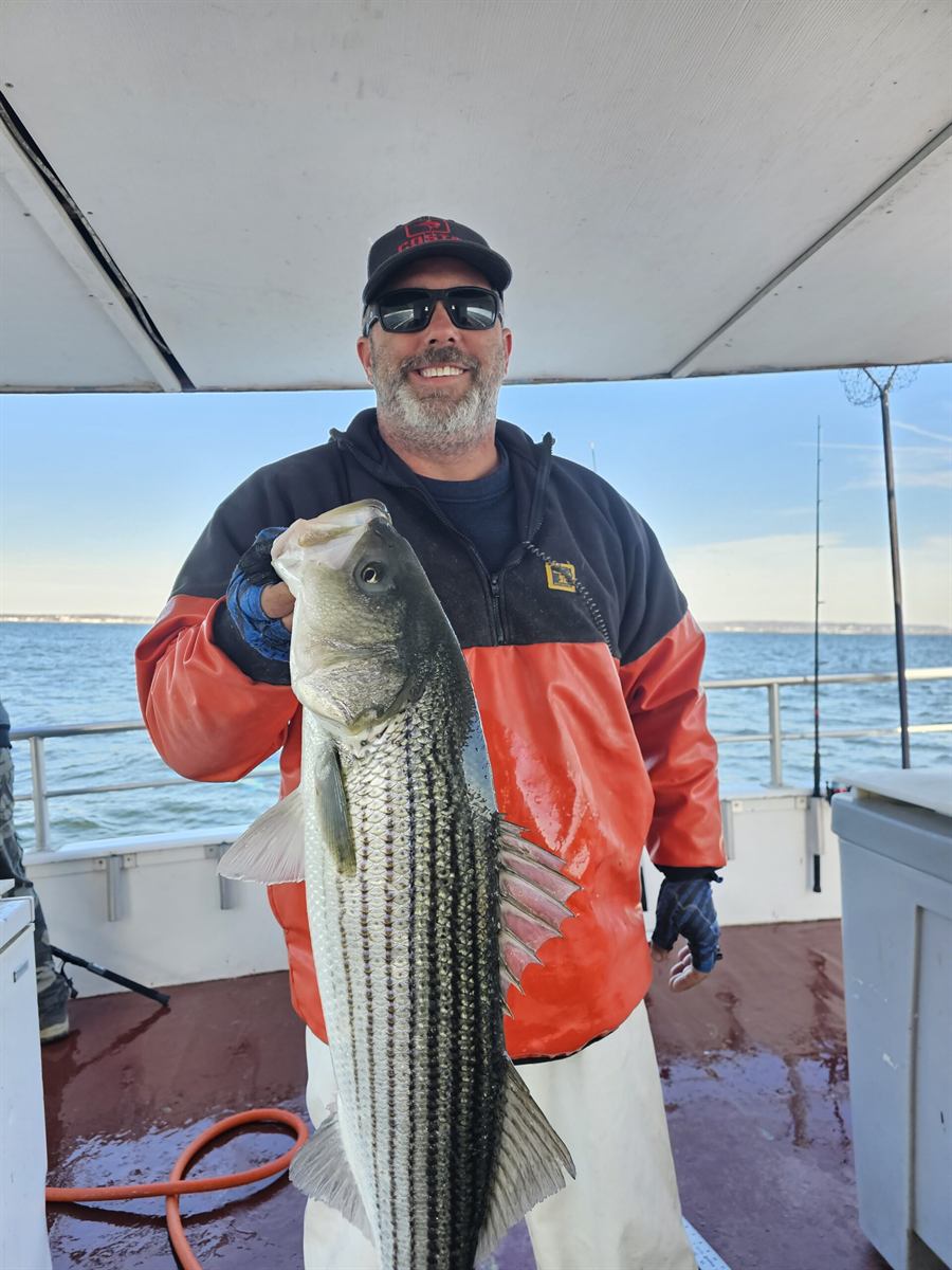 Angler holding a large striped bass on the Keyport Princess